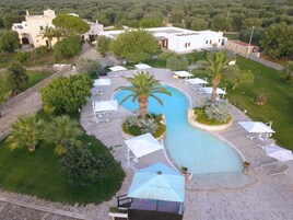 Un resort con una amplia piscina, tumbonas y palmeras.