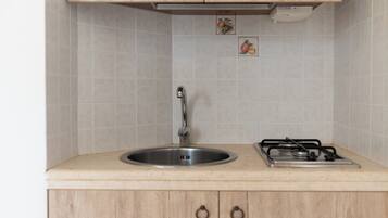 A kitchen with a sink, faucet, and stove.