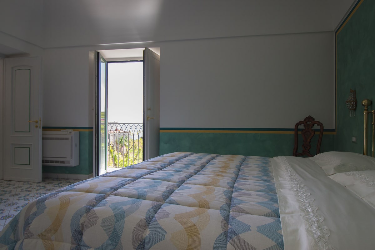 A bedroom with a bed, a window, and a door.