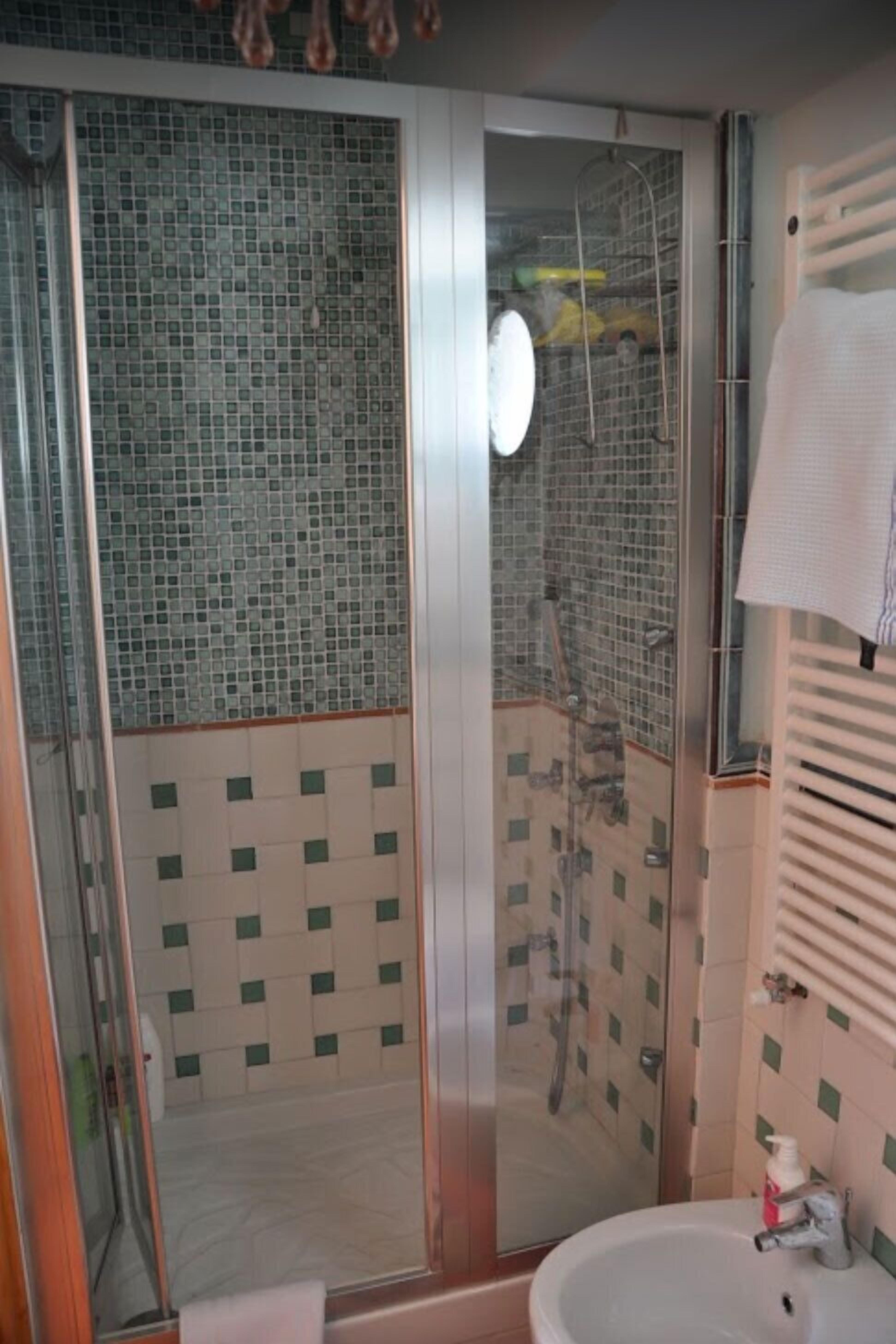 A bathroom with a glass-enclosed shower, a sink, and a mirror.