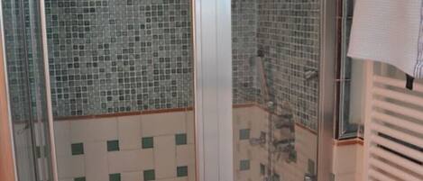 A bathroom with a glass-enclosed shower, a sink, and a mirror.