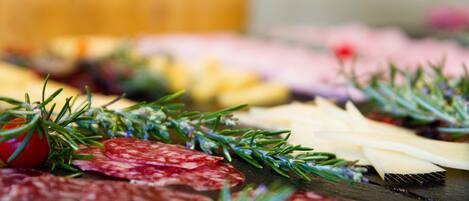 A charcuterie board with various meats, cheeses, and garnishes.