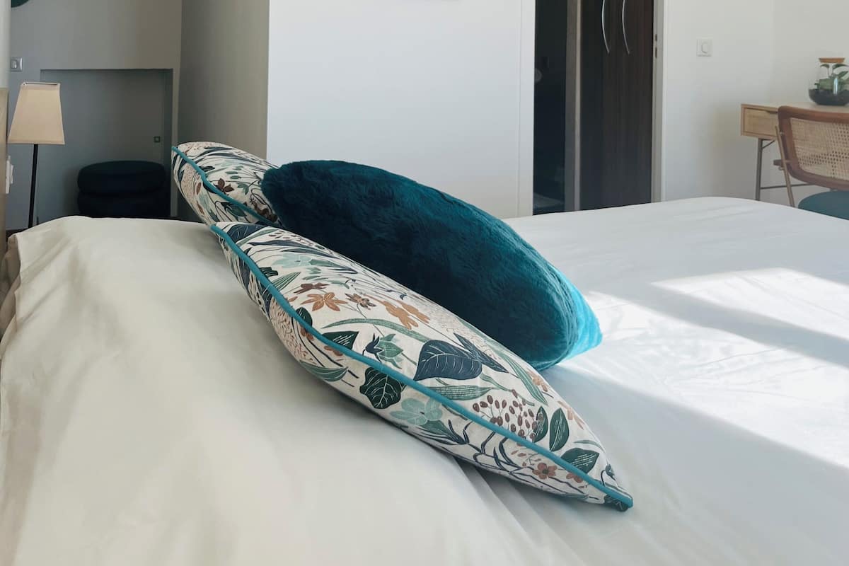 A hotel room with a bed, a nightstand, a lamp, a framed artwork, and a door.