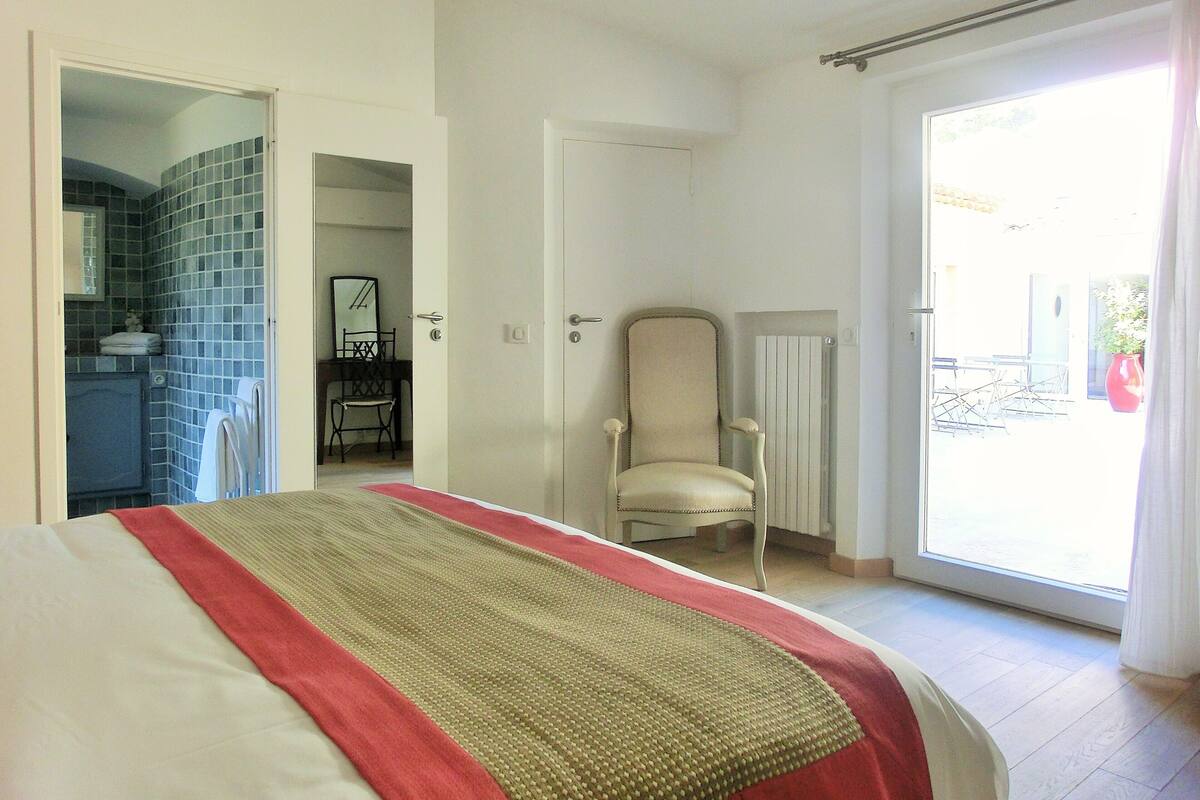 A hotel room with a bed, a chair, a radiator, and a view of the outside.