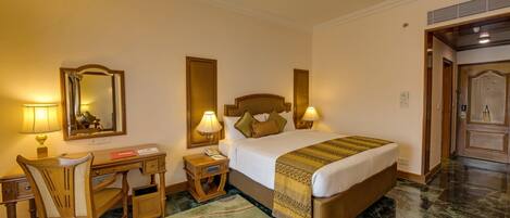 A hotel room with a bed, desk, chair, and a mirror.
