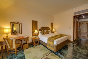 A hotel room with a bed, desk, chair, and a mirror. - The Ummed Ahmedabad Airport (Ahmedabad)