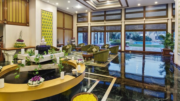 A hotel lobby with a reception desk, seating area, and large windows offering a view of the outdoors. - The Ummed Ahmedabad Airport (Ahmedabad)