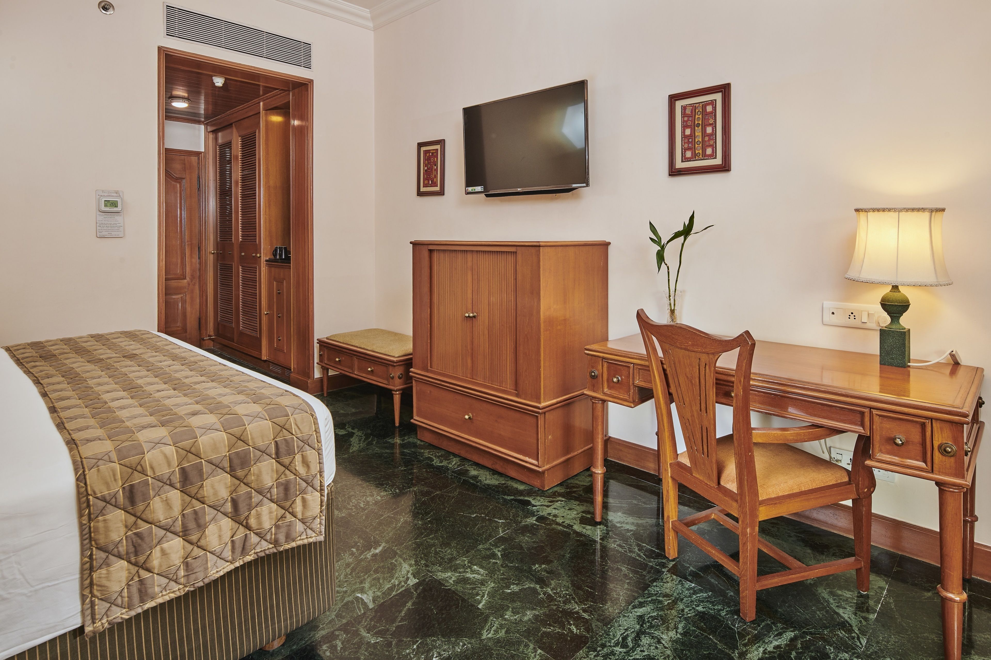 Een hotelkamer met een bed, een bureau, een stoel, een televisie en een kast.