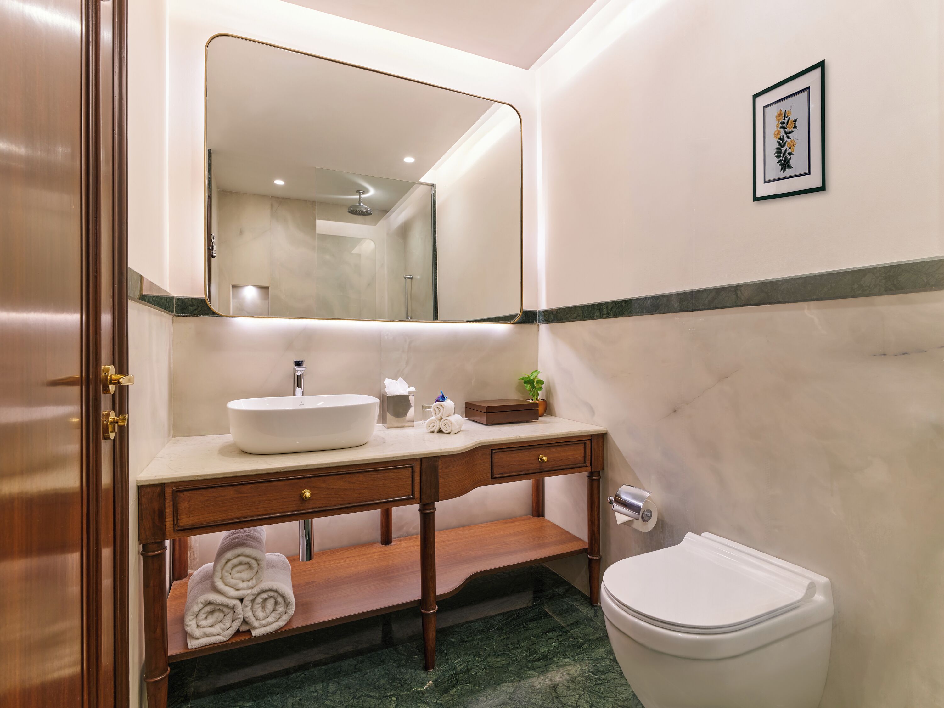 A bathroom with a large mirror, a sink, a toilet, and a towel rack.