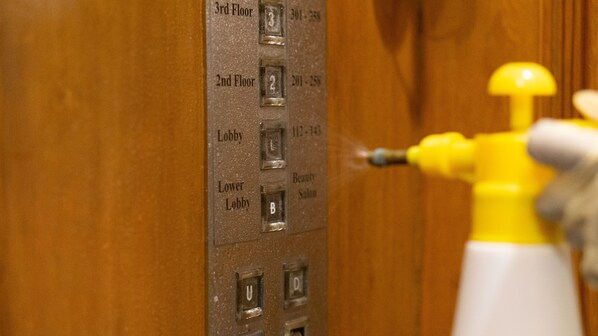 A hotel elevator with floor indicators and a fire extinguisher mounted on the wall.