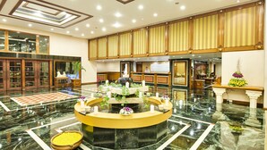 A spacious lobby with a marble floor, a central fountain, and a reception desk. - The Ummed Ahmedabad Airport (Ahmedabad)