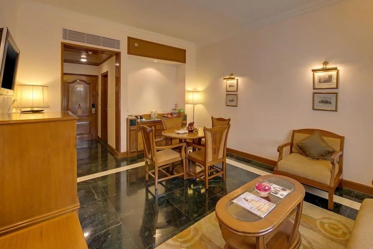 Une chambre d’hôtel comprenant un coin repas, un canapé, une table basse et un téléviseur.
