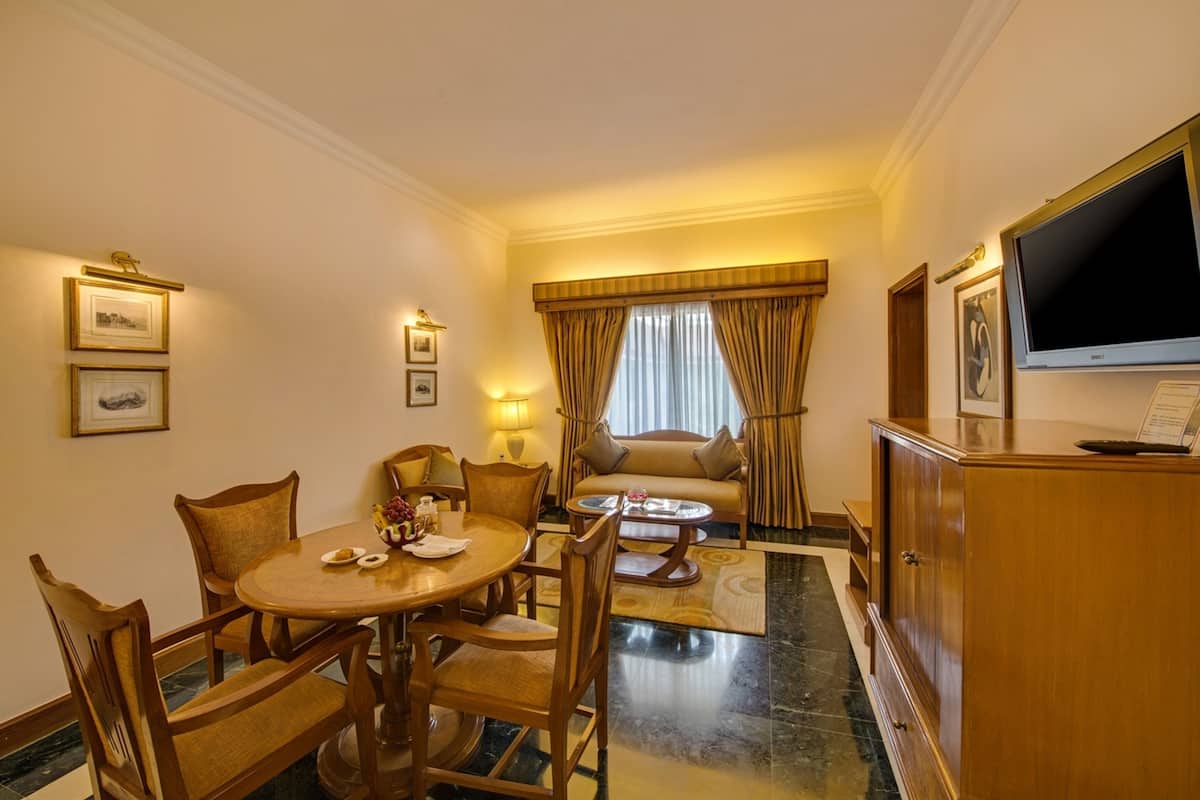 A hotel room with a dining area, a sofa, a TV, and a cabinet.