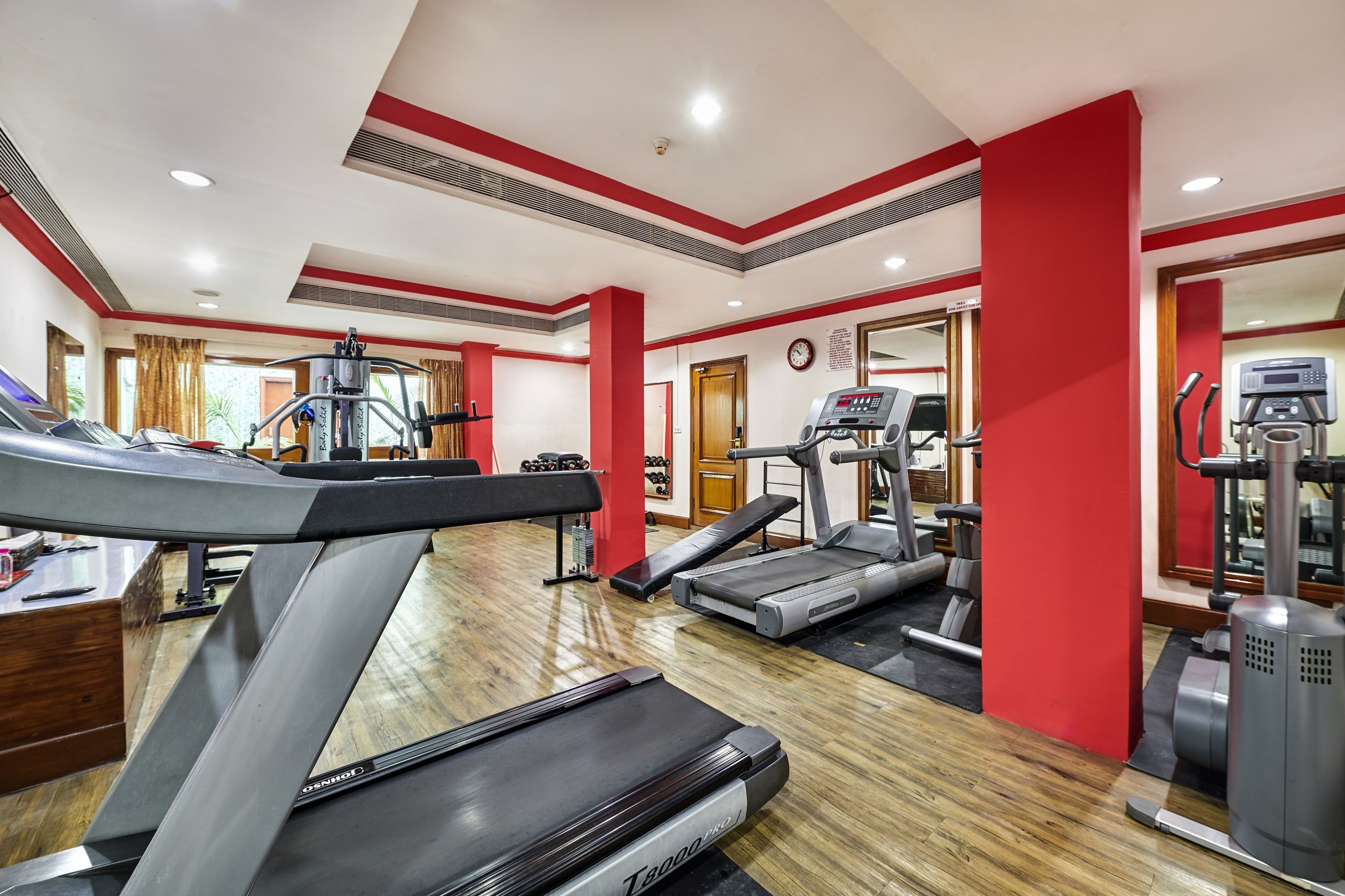 Un gimnasio con cintas de correr, máquinas elípticas y equipo de pesas.