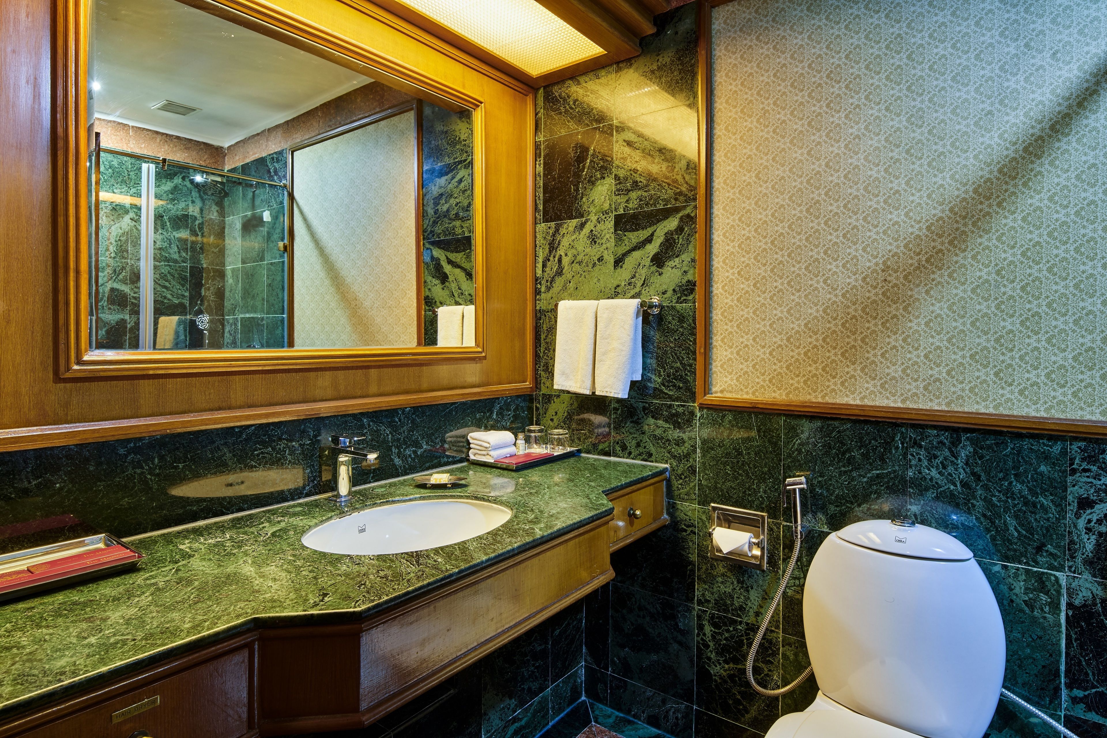 A bathroom with a marble sink, a large mirror, and a toilet.