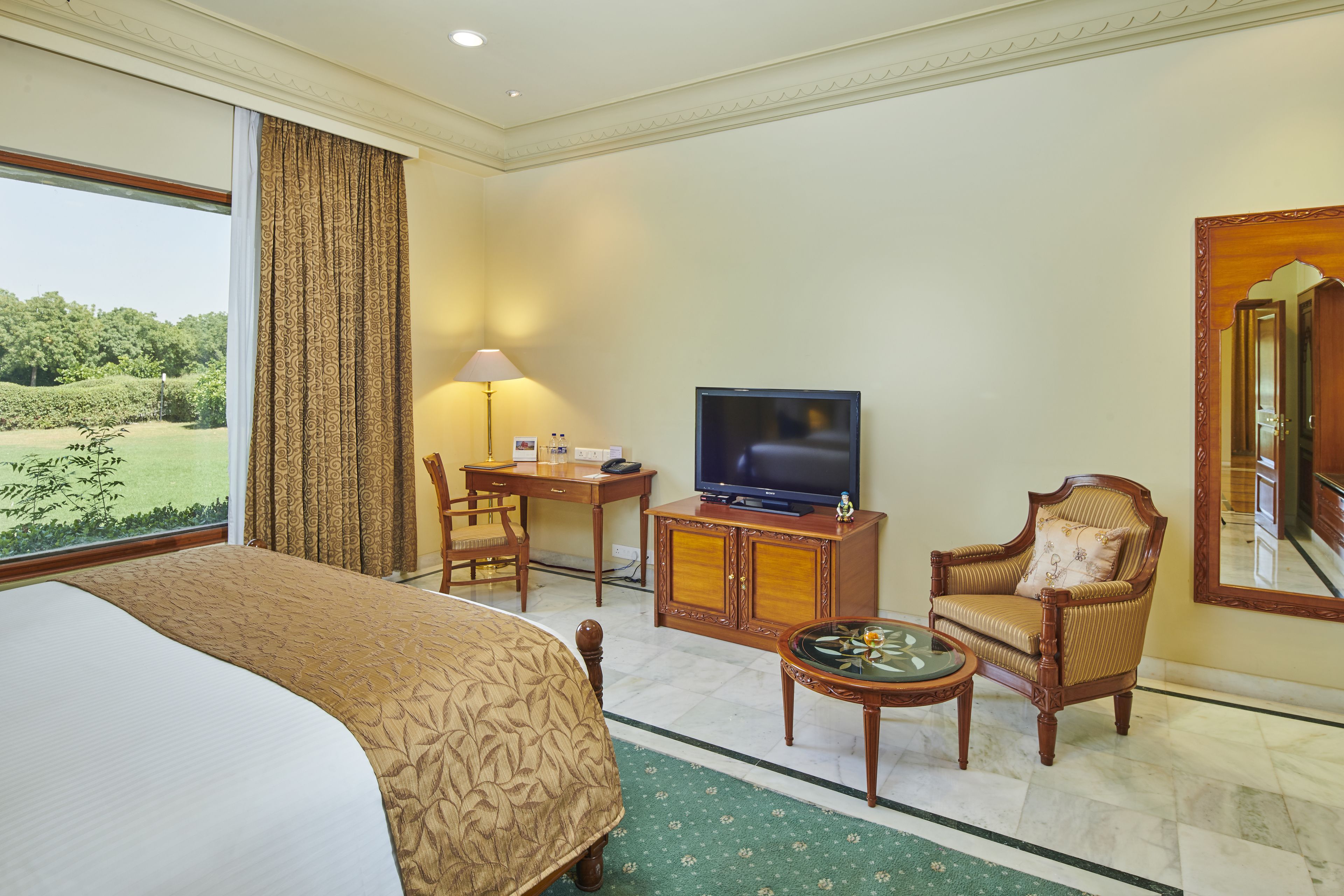 A hotel room with a bed, a television, a desk, a chair, and a view of the outdoors.