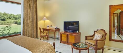 A hotel room with a bed, a television, a desk, a chair, and a view of the outdoors.
