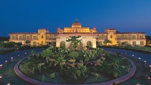 A large, ornate building with a central dome and multiple wings, surrounded by a well-manicured garden with pathways and lit columns. - The Ummed Jodhpur Palace Resort & Spa (Jodhpur)