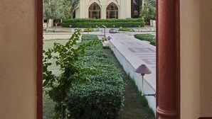 An architectural view through an archway, featuring a building with a dome and arched windows, surrounded by a well-maintained garden and pathway. - The Ummed Jodhpur Palace Resort & Spa (Jodhpur)