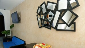 A room with a blue sofa, a fruit basket on a wooden table, and a wall decorated with multiple mirrors.