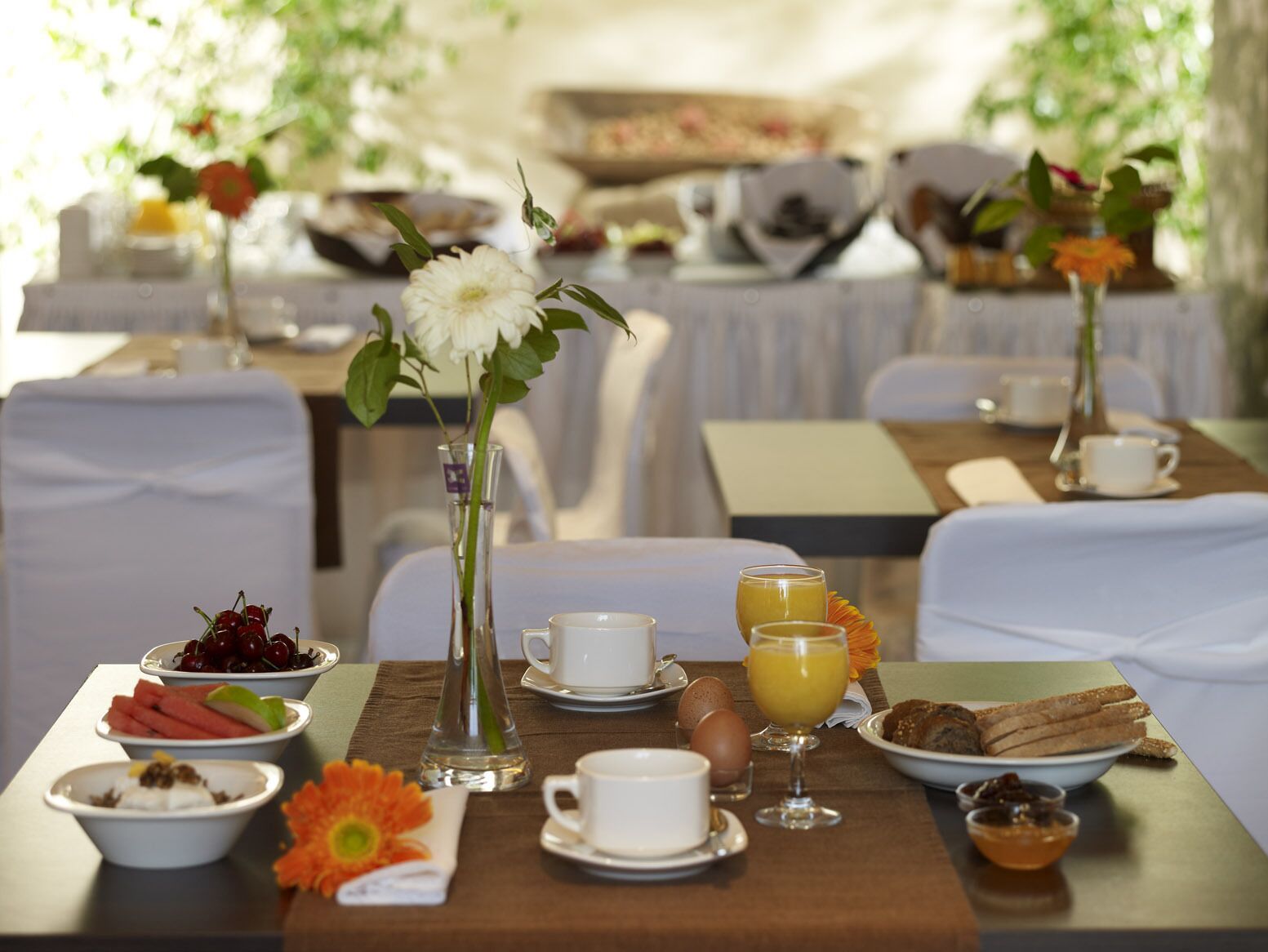 Une table dressée pour le petit-déjeuner, avec une variété d'aliments et de boissons, notamment des œufs, des toasts et des fruits.