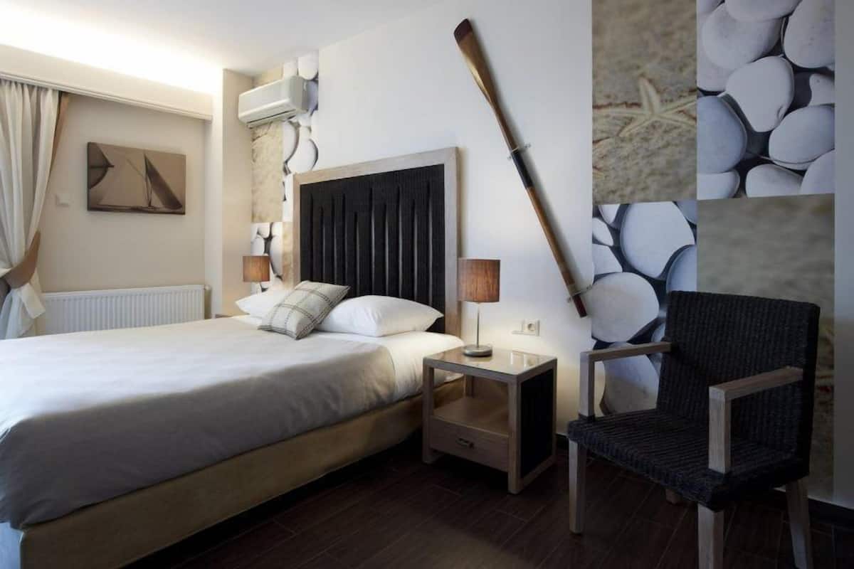 Una camera d'albergo con un letto, comodini, una sedia e opere d'arte alle pareti.