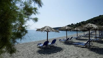 På stranden, solstolar, parasoller och volleyboll