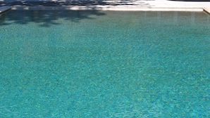 A clear, rectangular swimming pool with a tiled edge and a shadow of a tree on the surface. - Belle Helene Hotel (East Mani)