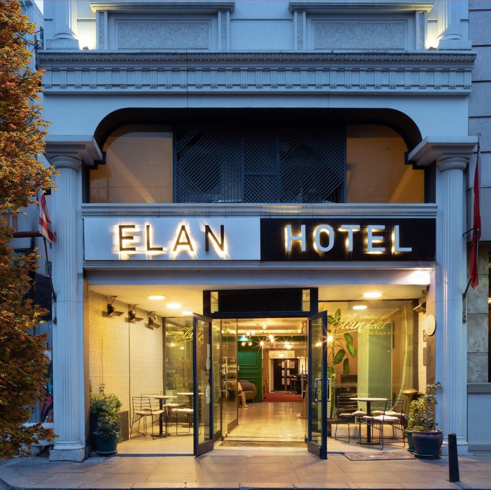 L’entrée de l’hôtel Elan se distingue par sa façade en verre, son espace extérieur aménagé pour s’asseoir et son architecture classique.