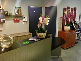 Un mostrador de recepción con una orquídea en maceta, un pecera y un cuadro en la pared.