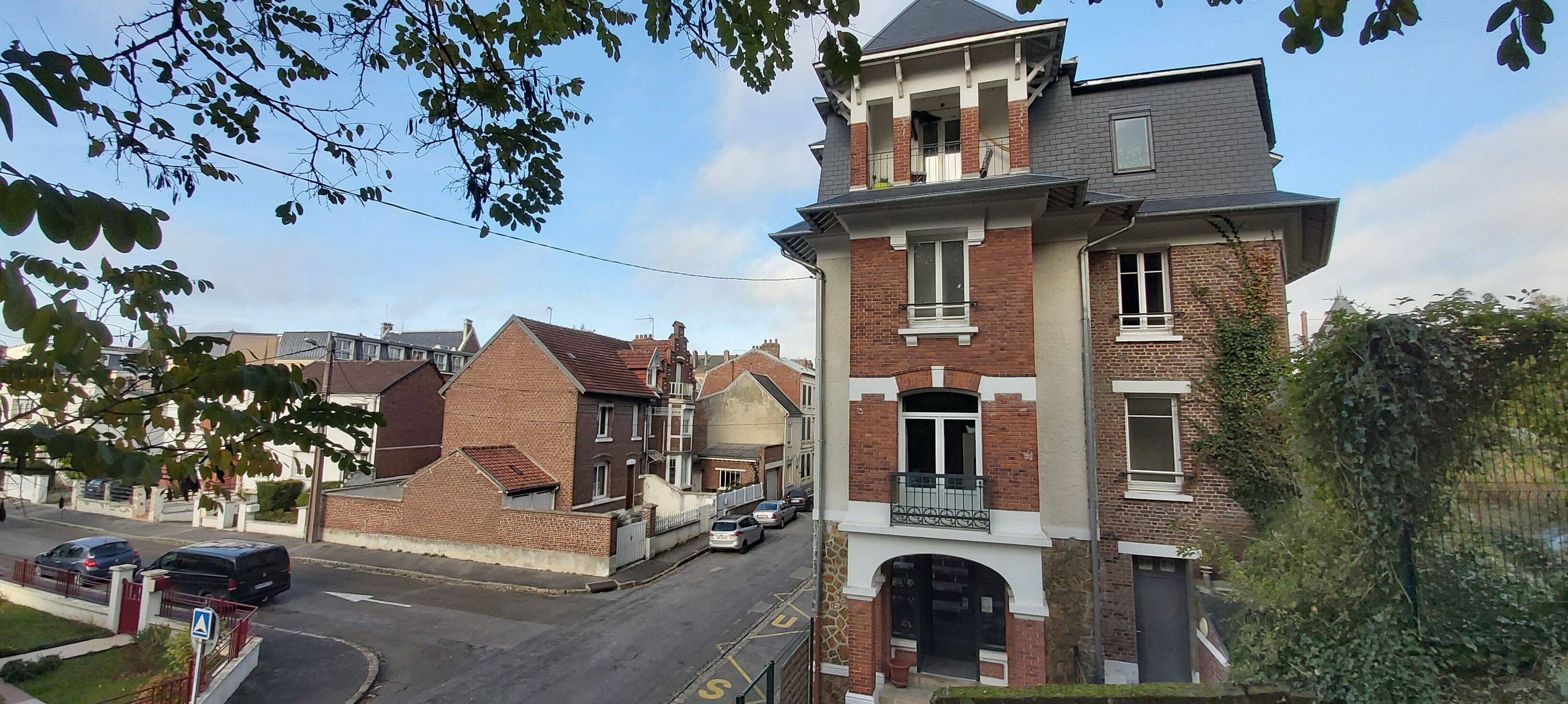 A two-story residential building with a brick facade, a balcony on the upper floor, and a garage entrance.