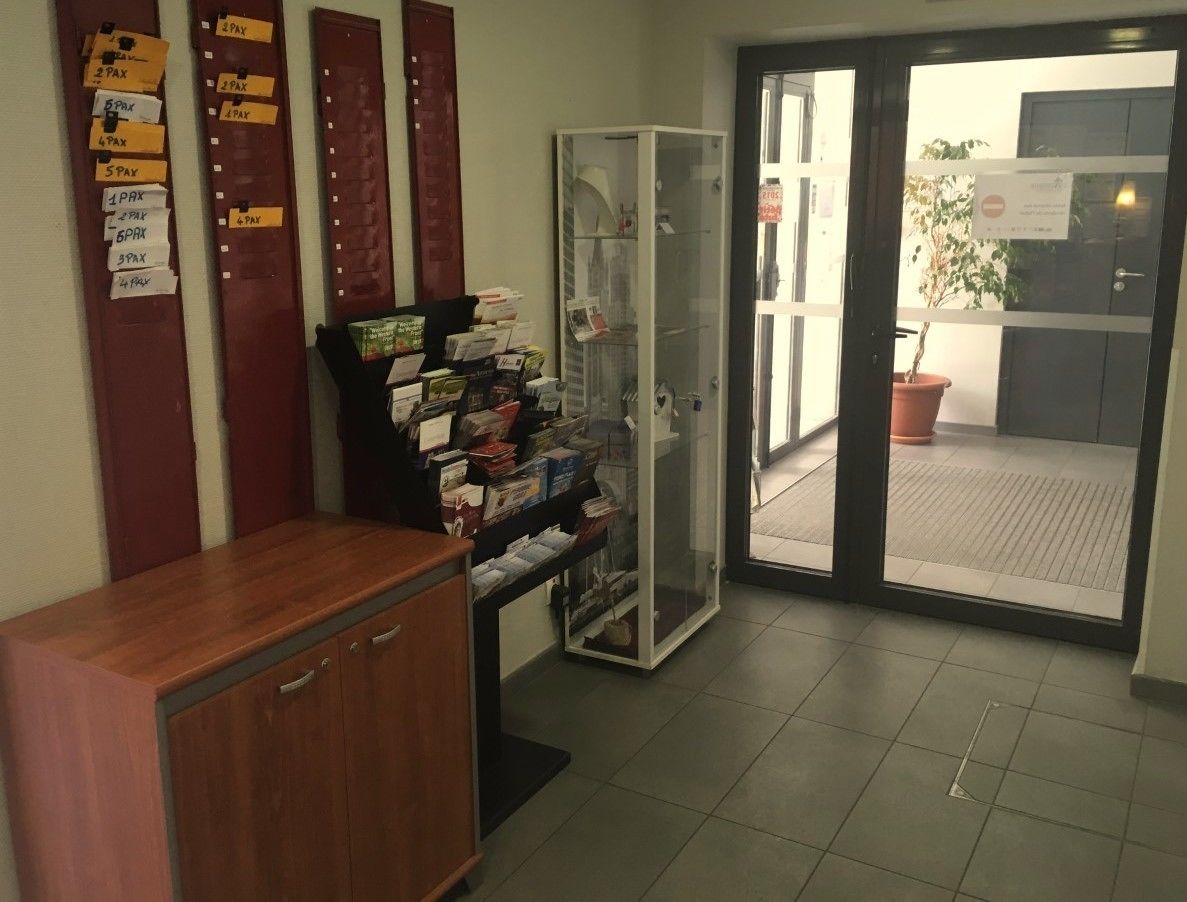 A reception area with a wooden desk, a glass display case with brochures, and a door leading outside.