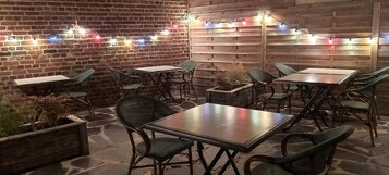 Un patio al aire libre con paredes de ladrillo, bancos y mesas de madera.