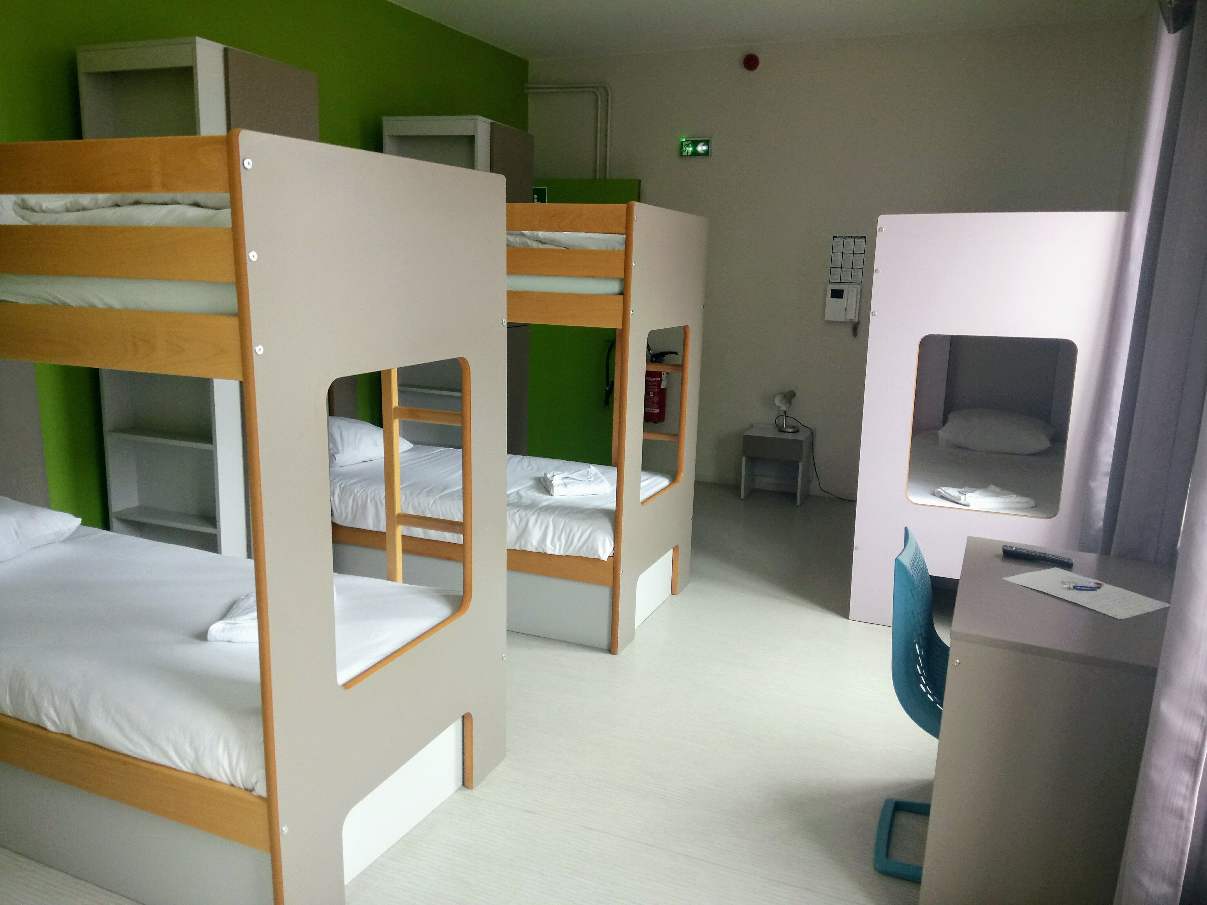 Un dormitorio con literas, un escritorio, una silla y una mesita.