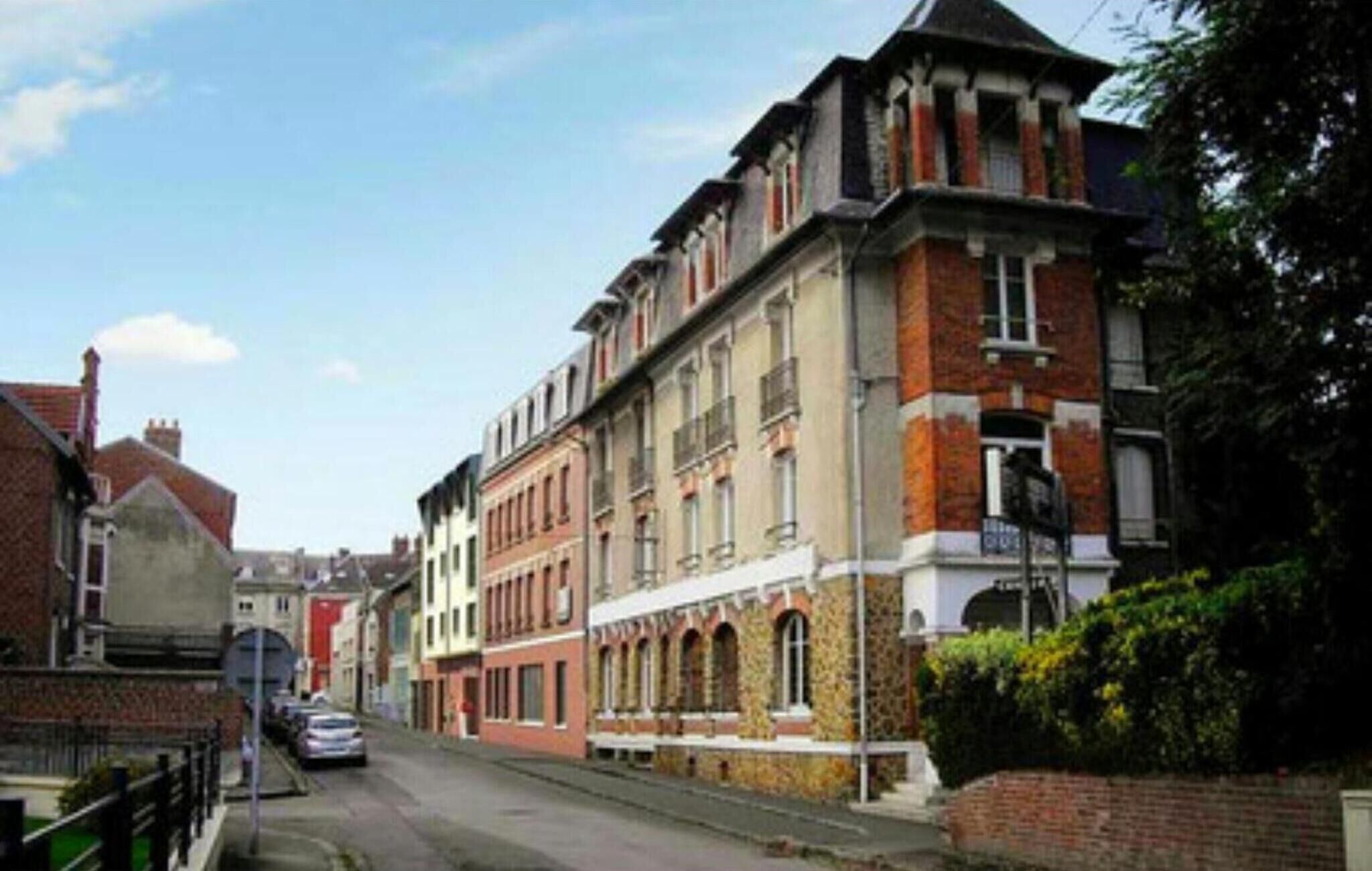 A street view of a row of historic buildings with a mix of architectural styles, including a prominent building with a corner turret and arched windows.