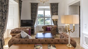 Een luxueuze woonkamer met een grote bank, een bijzettafeltje, een televisie en een kroonluchter.