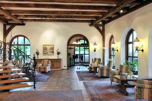 Un interior espacioso con una escalera de madera, ventanas en arco y una combinación de zonas de estar.