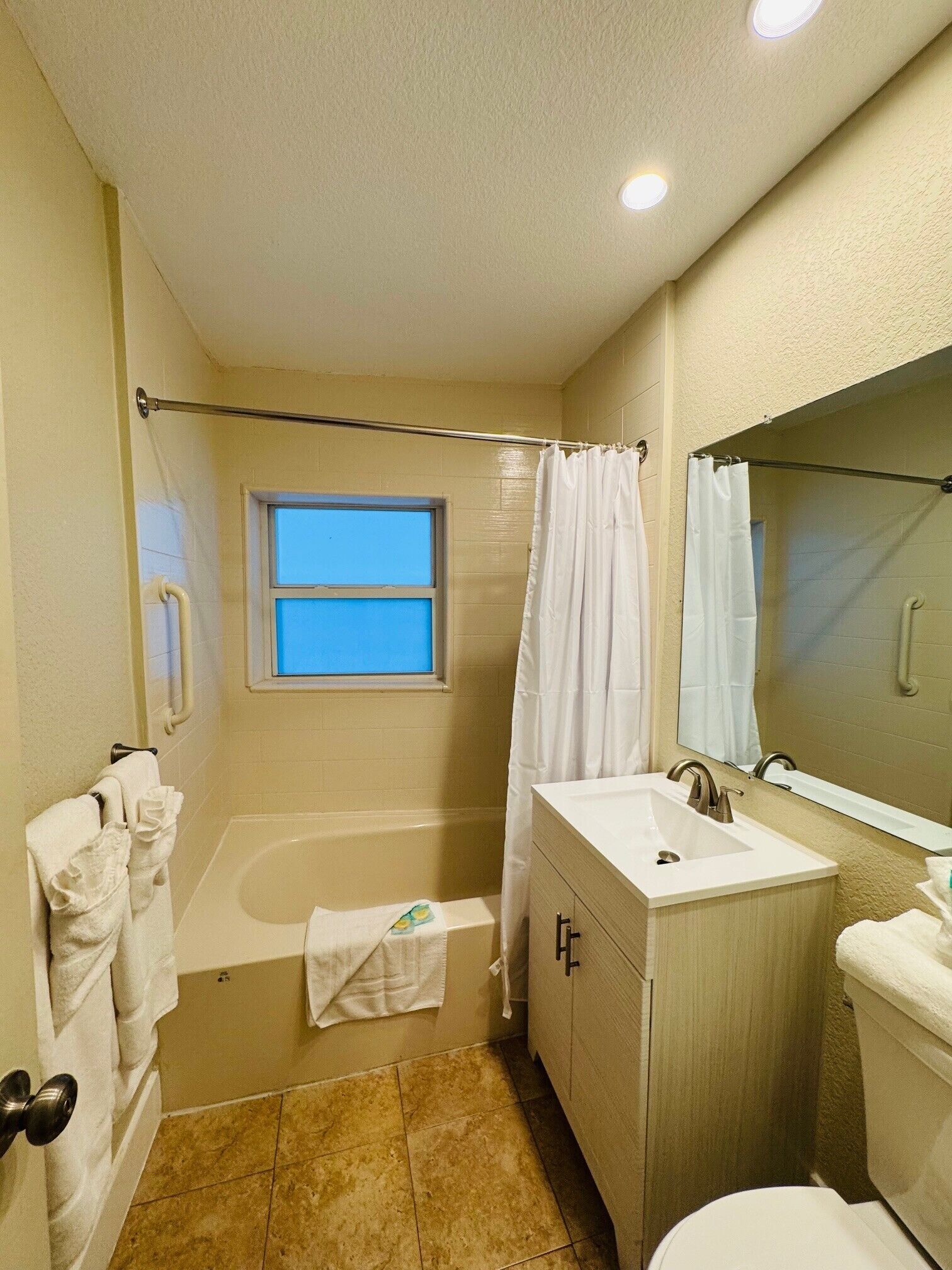 A bathroom with a bathtub, a sink, a toilet, and a window.