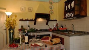 A kitchen with a checkered tablecloth, a vase of flowers, and various food items.
