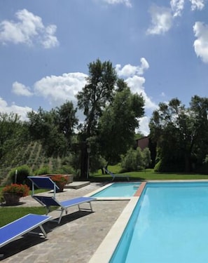 Une piscine avec des chaises longues et un ciel dégagé.