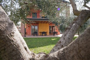 A modern house with a patio, a brick wall, and a tree in the foreground. - Agritur Le Sigalette (Valeggio sul Mincio)