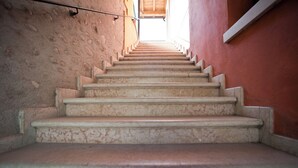 A set of marble stairs leading upwards, with a textured wall on the left and a plain wall on the right.