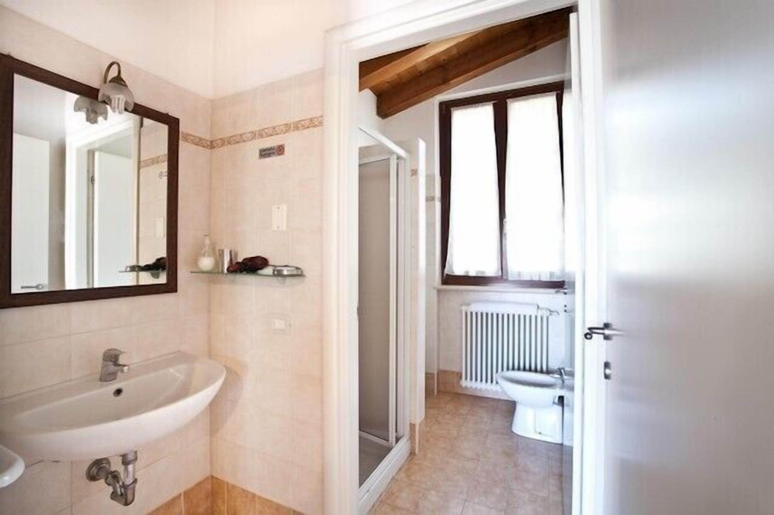 A bathroom with a sink, mirror, shower, and toilet.