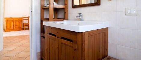 Un meuble-lavabo en bois avec un lavabo blanc et un miroir au-dessus.