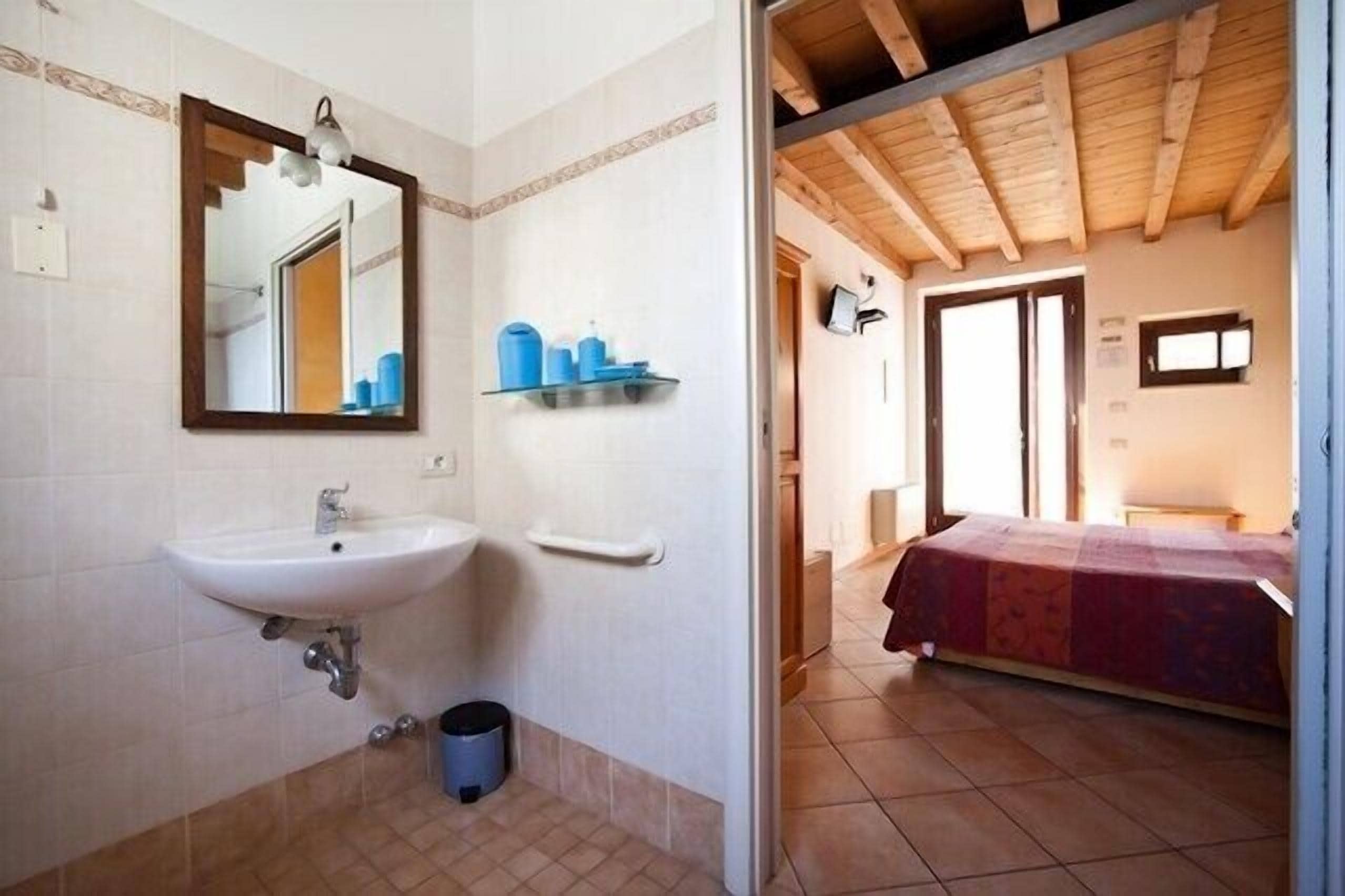 A bathroom with a sink, mirror, and shelves with toiletries.