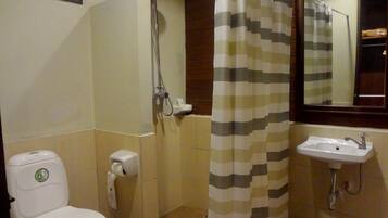 A bathroom with a toilet, a shower, and a sink.
