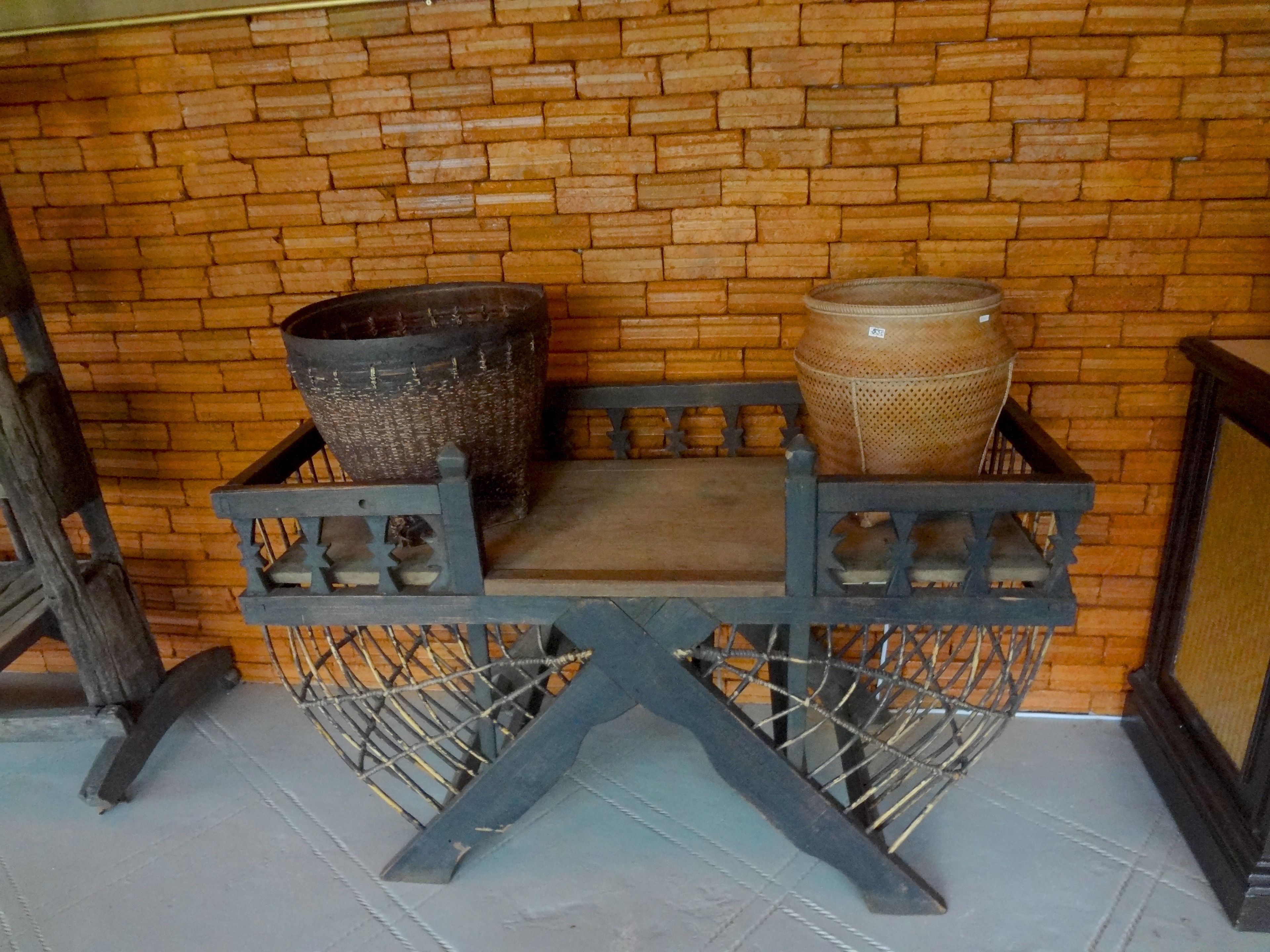Una mesa de madera rústica con dos macetas de cerámica grandes encima, frente a un muro de ladrillo.