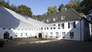 Un bâtiment blanc doté d’un grand patio couvert, de nombreuses fenêtres et d’une porte.