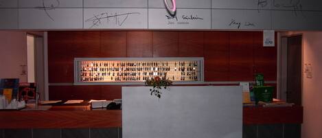 A bar area with a counter, a display of bottles, and a wall with signatures.