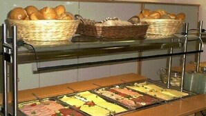 Un buffet avec plusieurs présentoirs de plats et des paniers de pain.